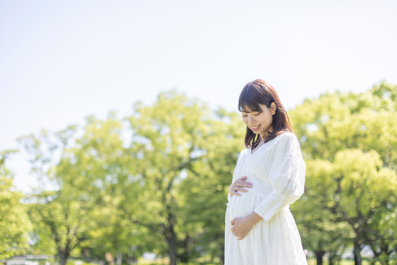 新緑の公園で微笑む妊婦さん